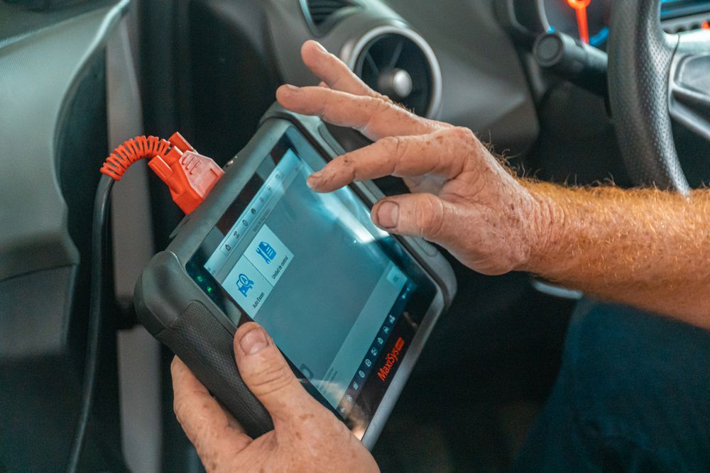 Mechanic using a diagnostic tool inside a car